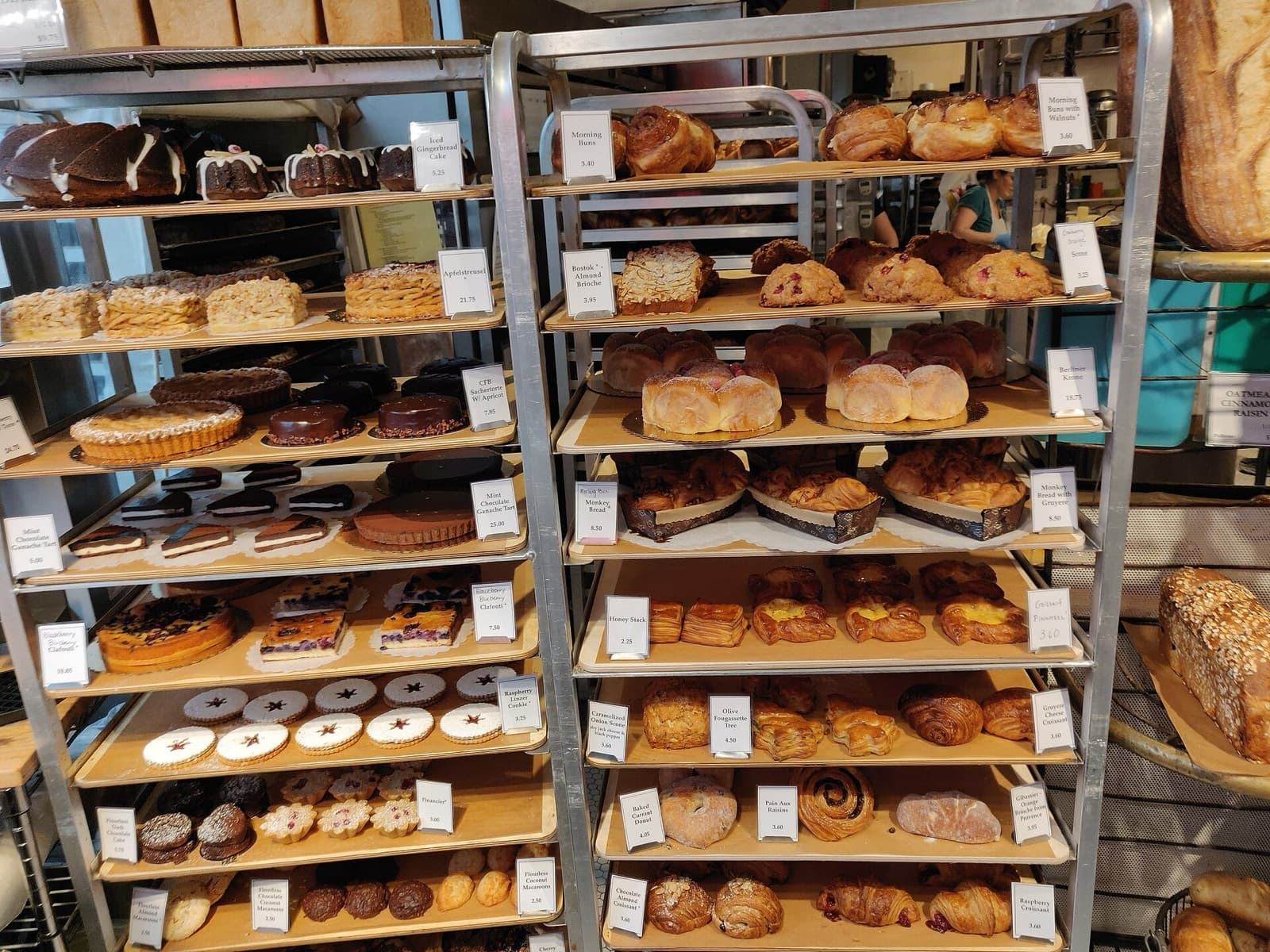 Des étagères de boutique garnies de pains, de viennoiseries et de tartes, chacun avec son étiquette