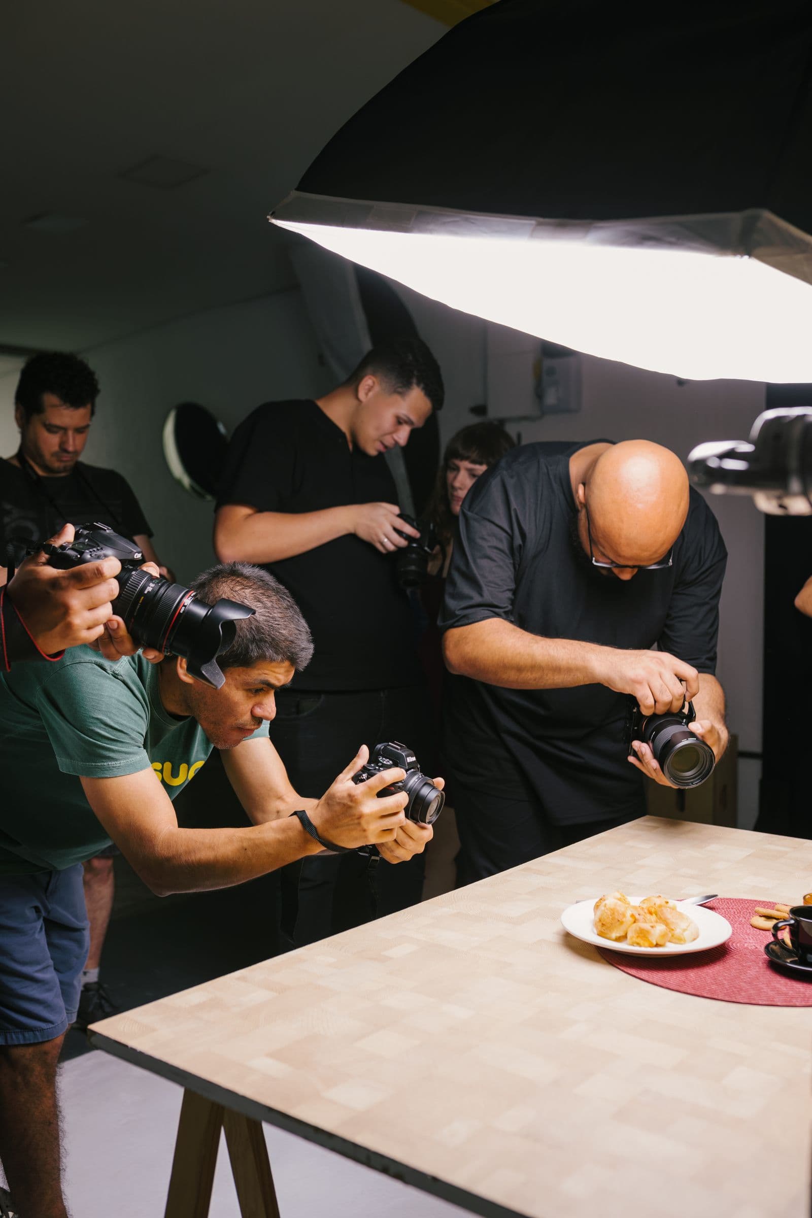 Des photographes réalisent en studio des prises de vue d'un plat sous un grand réflecteur